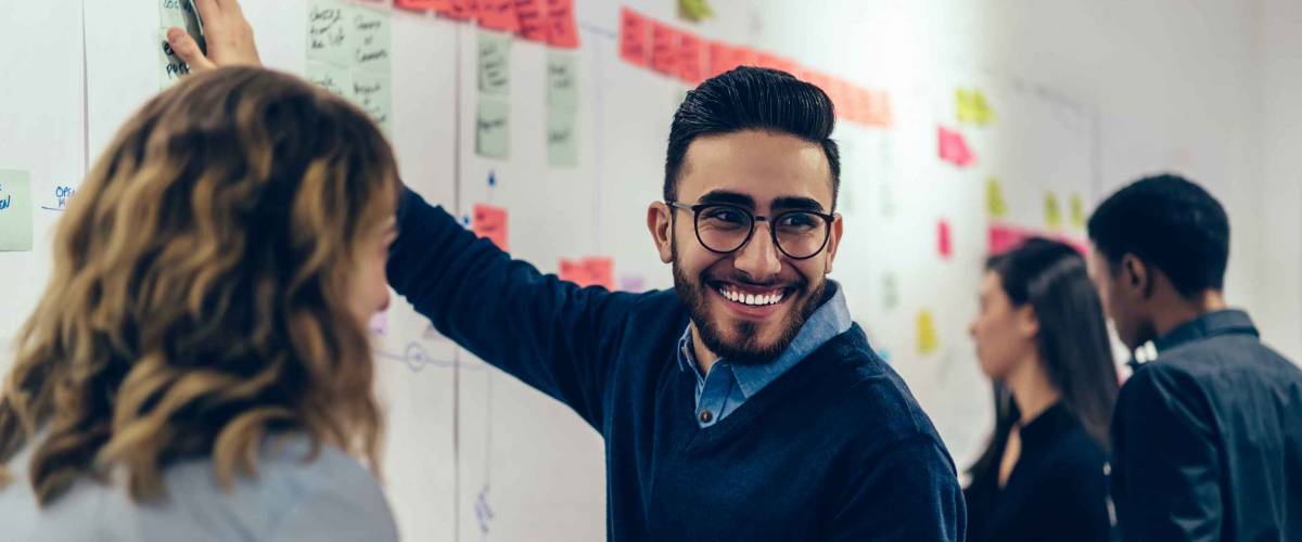 Positive young man laughing while collaborating with colleagues