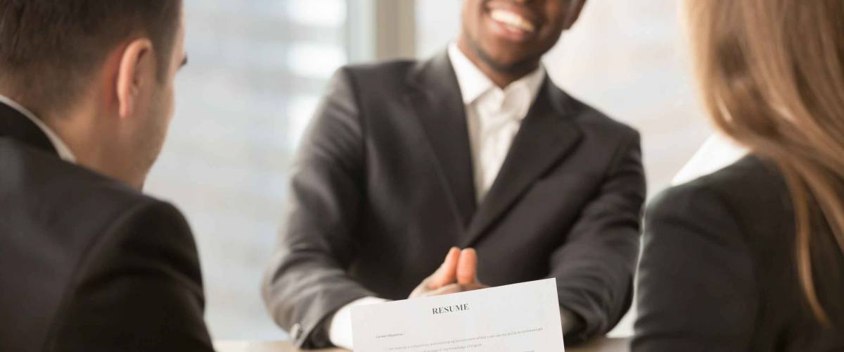 Employers or recruiters review cv of black confident job applicant smiling at background during employment interview