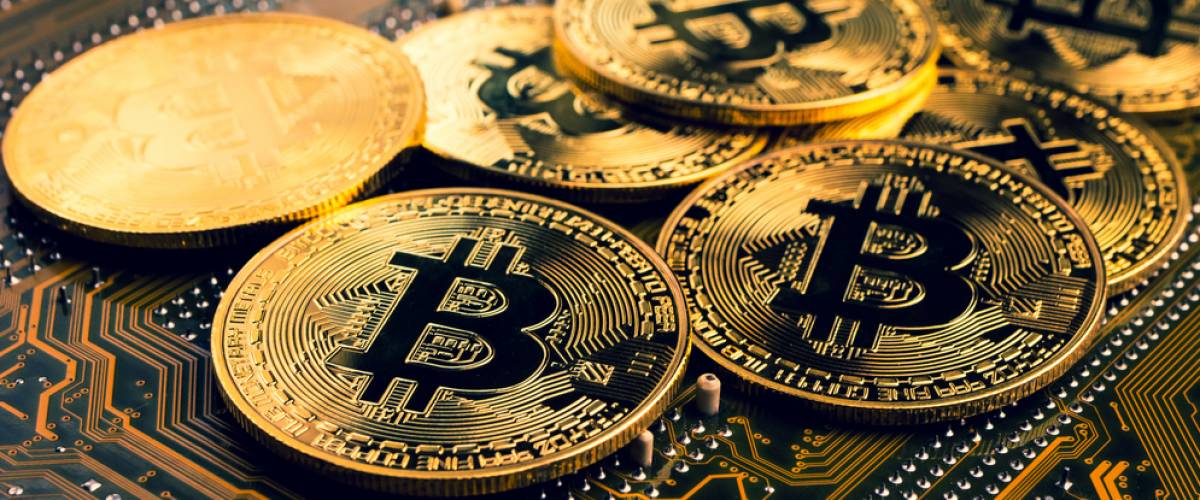 Golden coins with bitcoin symbol on a mainboard.