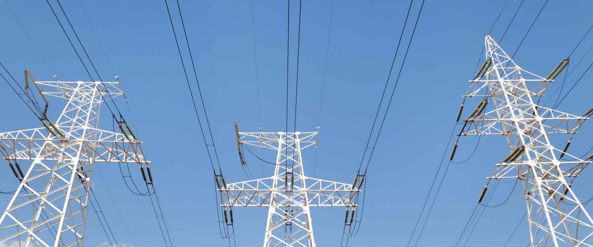 Power transmission high voltage lines on the white supports against blue sky