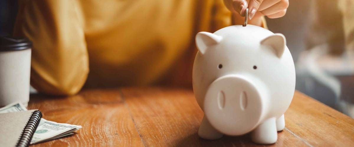 woman hand putting money coin into piggy for saving money wealth and financial concept.