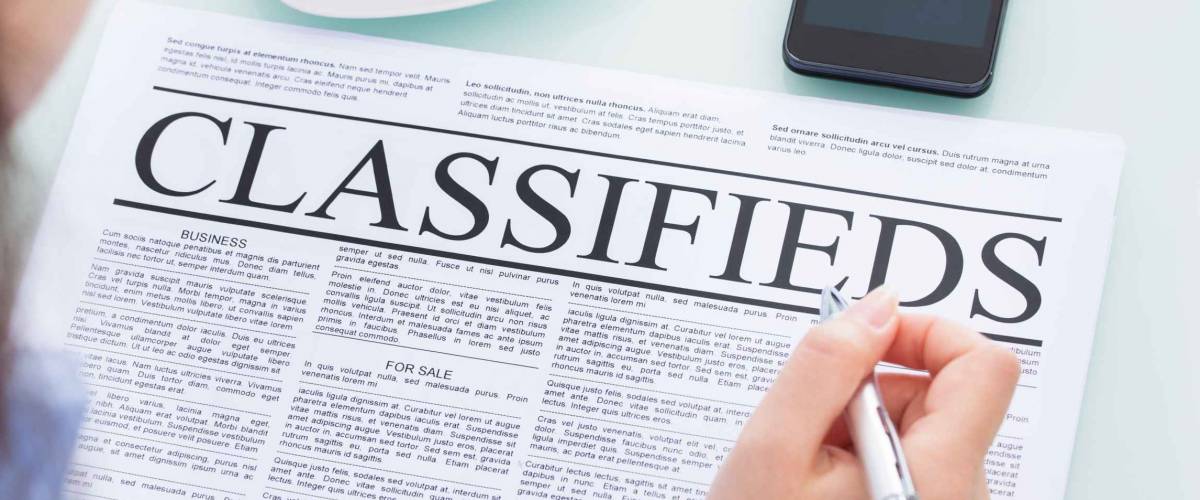 Close-up Of A Businesswoman Holding Pen Reading Classifieds On Newspaper
