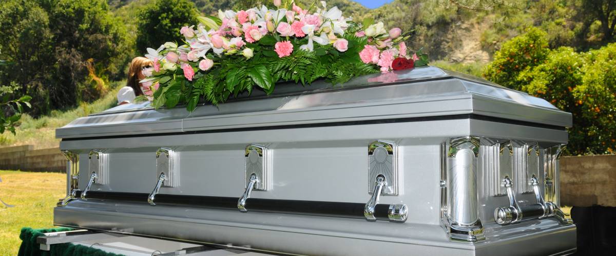 Silver casket at funeral with flowers