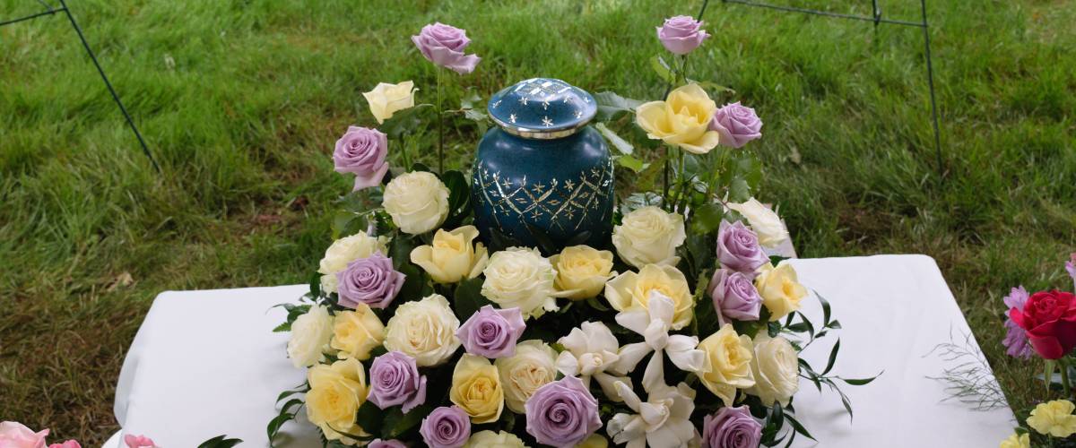 Funeral urn on table with yellow and purple flowers