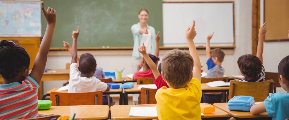 Pupils raising their hands during class at the elementary school