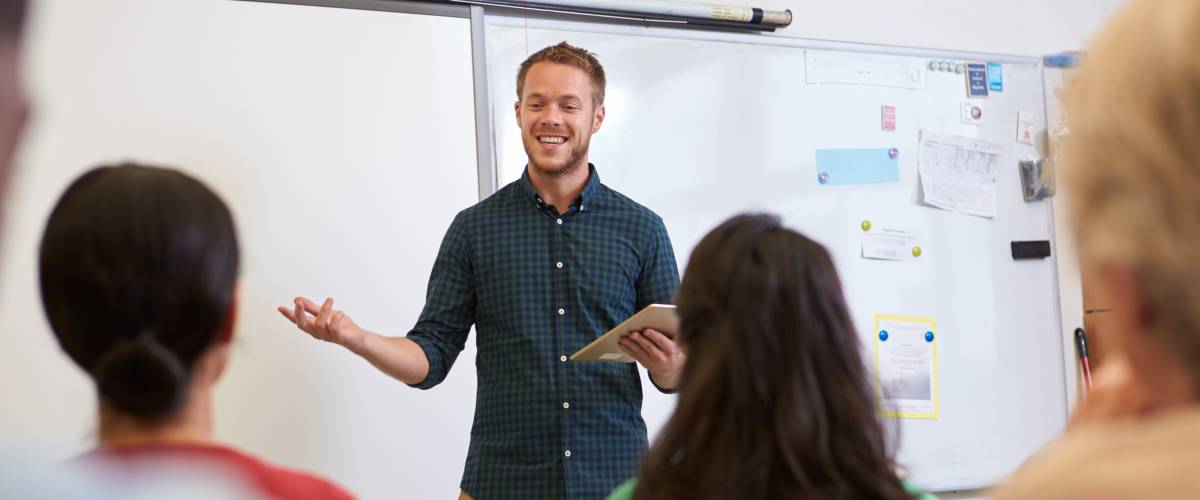 Male teacher listening to students at adult education class