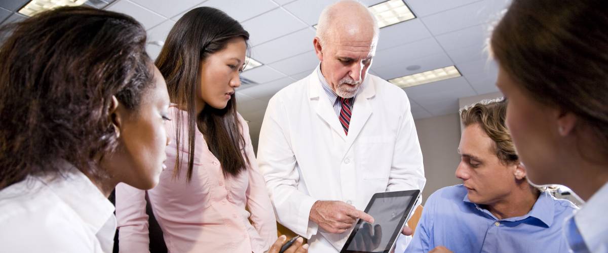 Professor wearing lab coat having discussion with college students