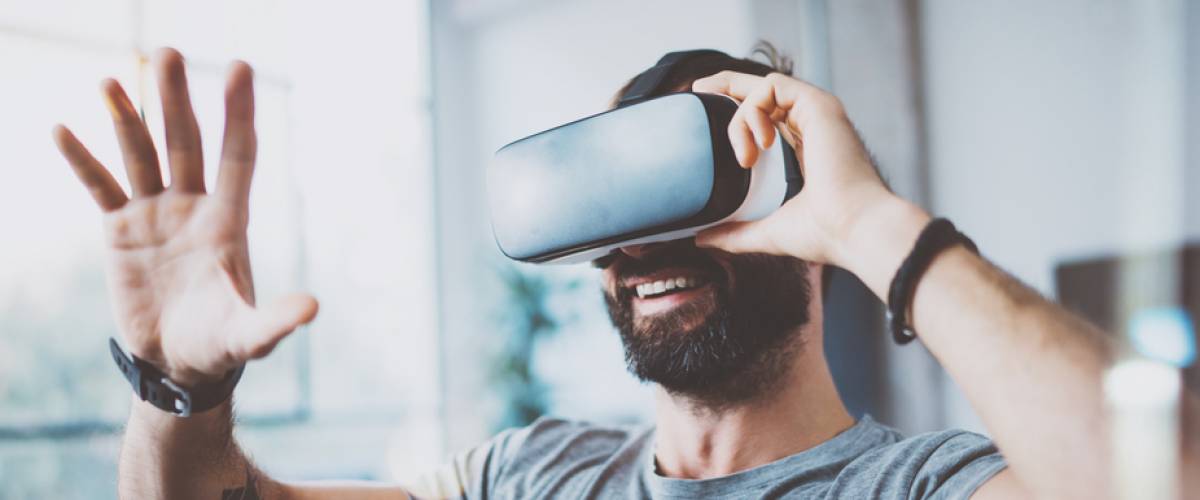 Young bearded man wearing virtual reality glasses in modern interior design coworking studio.