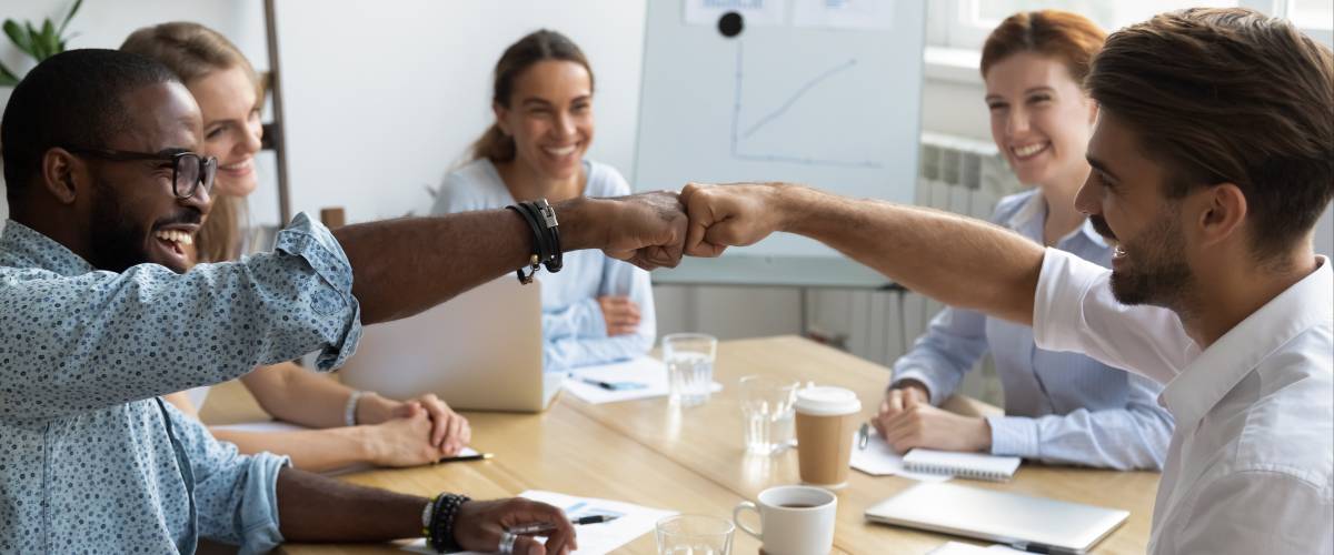 Diverse colleagues fist bumping greeting each other express friendship and respect.