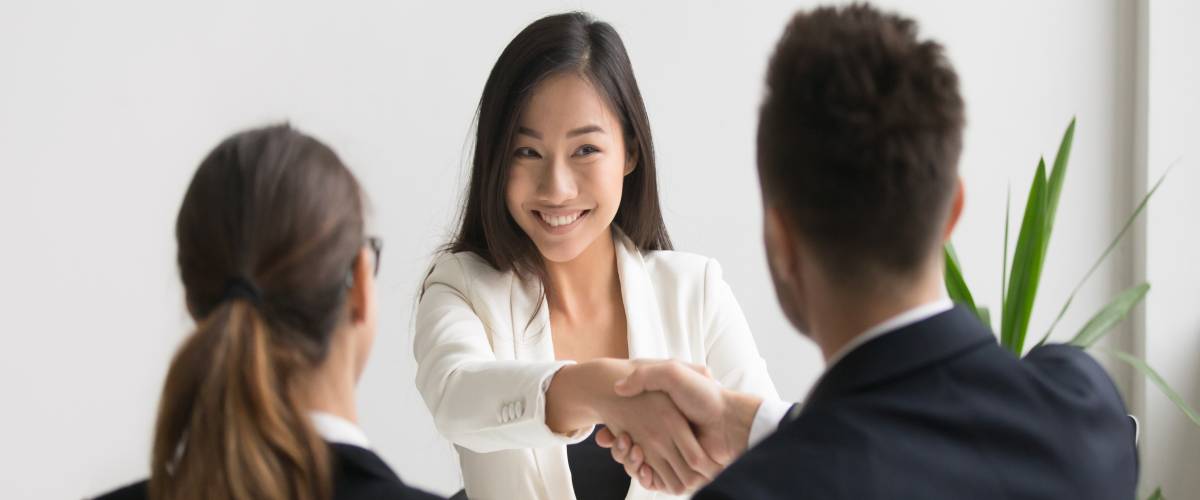 Smiling successful young asian applicant handshake with hr manager feels happy getting hired,