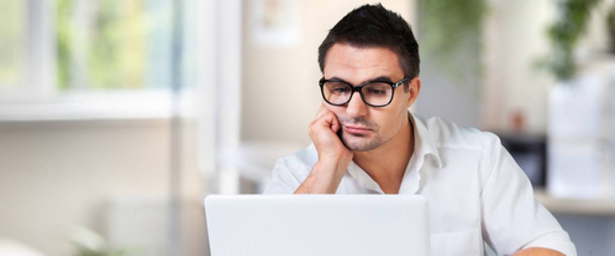 Thoughtful young man working online using laptop app