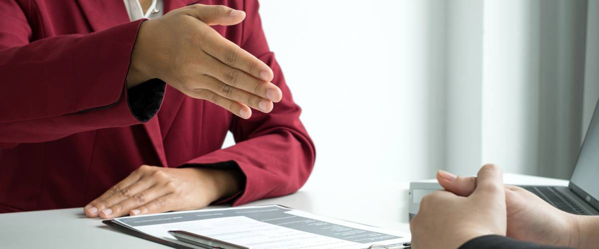 Business women holds out hand for handshake during job interview