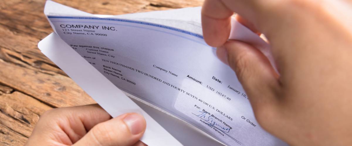 Cropped hands of businessman opening envelope with paycheck