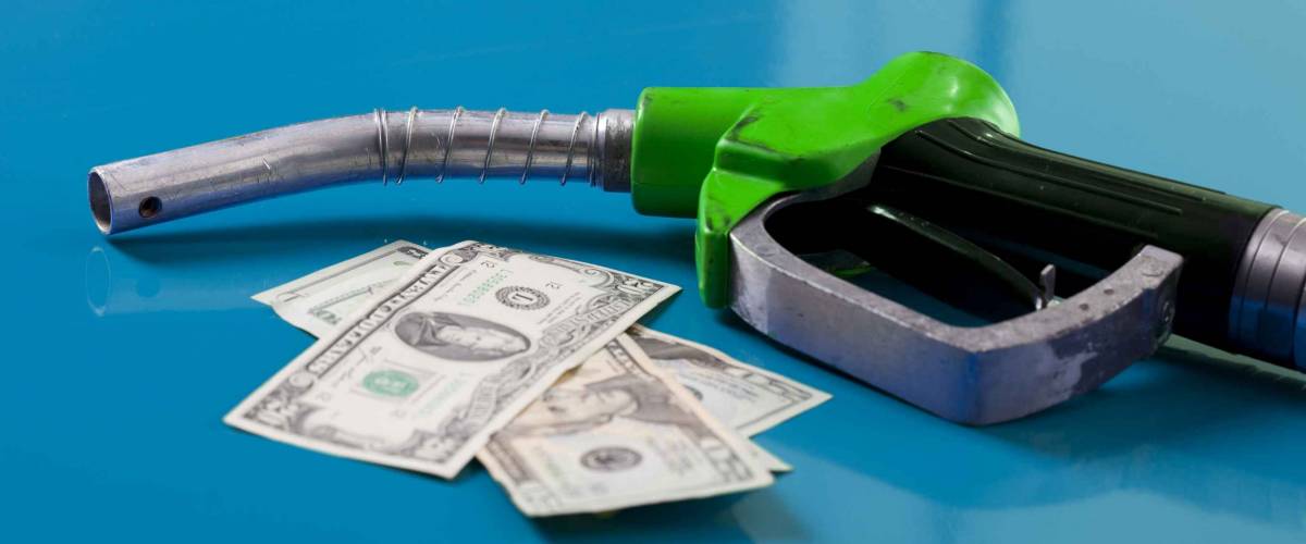 Gas price concept. American dollars and fuel nozzle