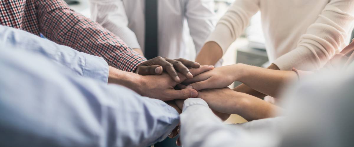 Close up view of young business people putting their hands together. Stack of hands. Unity and teamwork concept.