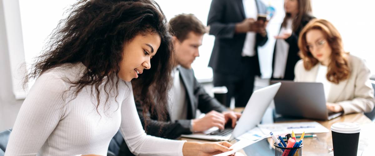 Concentrated african american woman doing paperwork, sitting in modern office on conference.