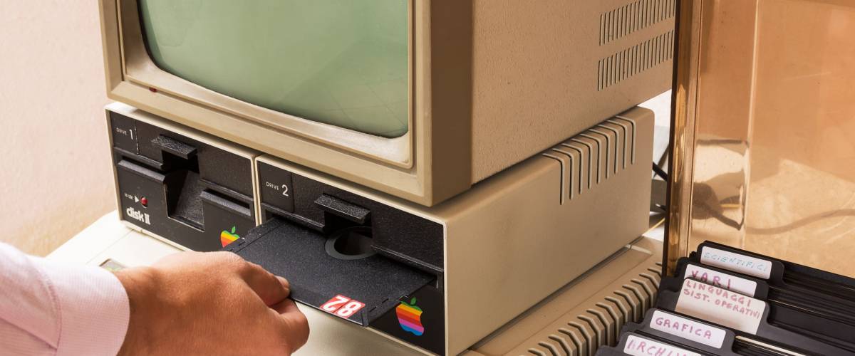 Cisternino, Italy - January 4, 2016: Aged Apple computer and hand insert floppy inside