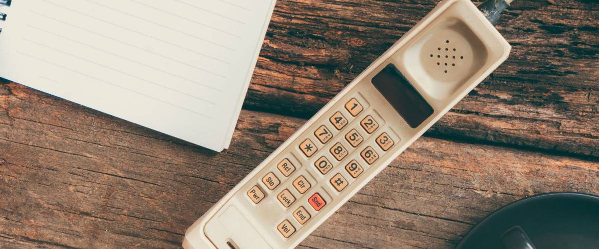 vintage mobile phone with blank paper note and cup of coffee (vintage style)