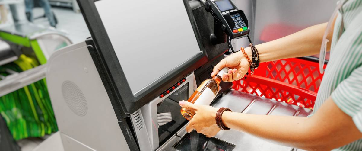 Woman scanning a wine bottle at a self checkout