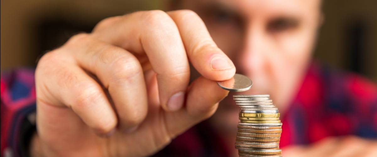 Man counts his coins on a table.