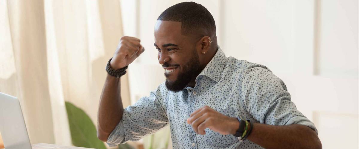Euphoric young black man celebrating receiving high paid job offer.