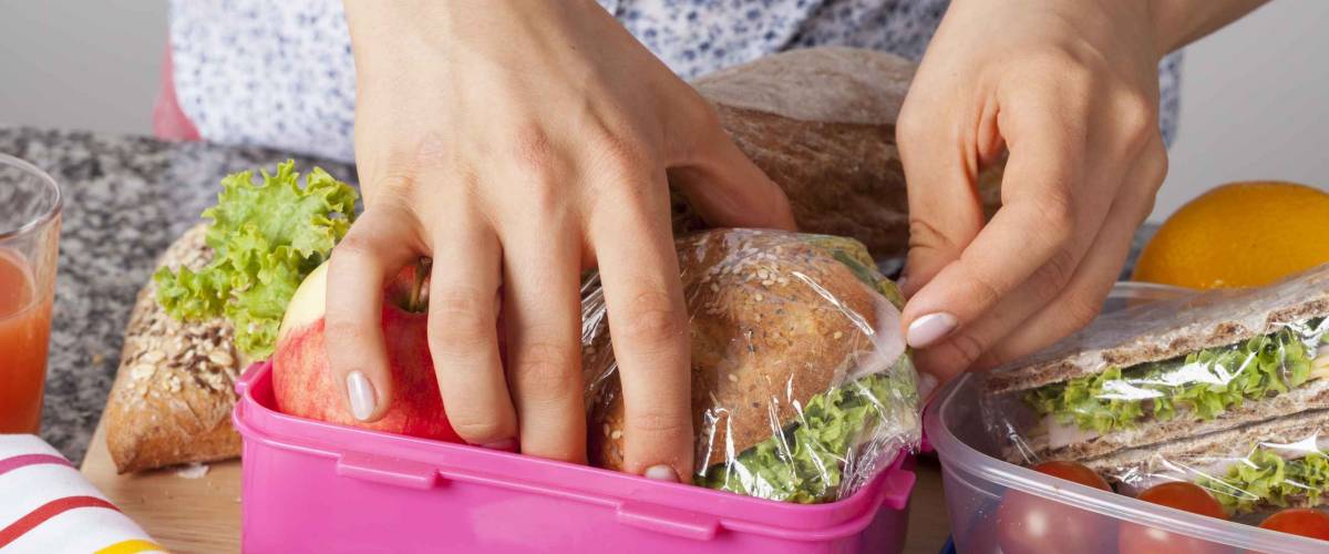 A closeup of hands packing snacks into a pink lunch box