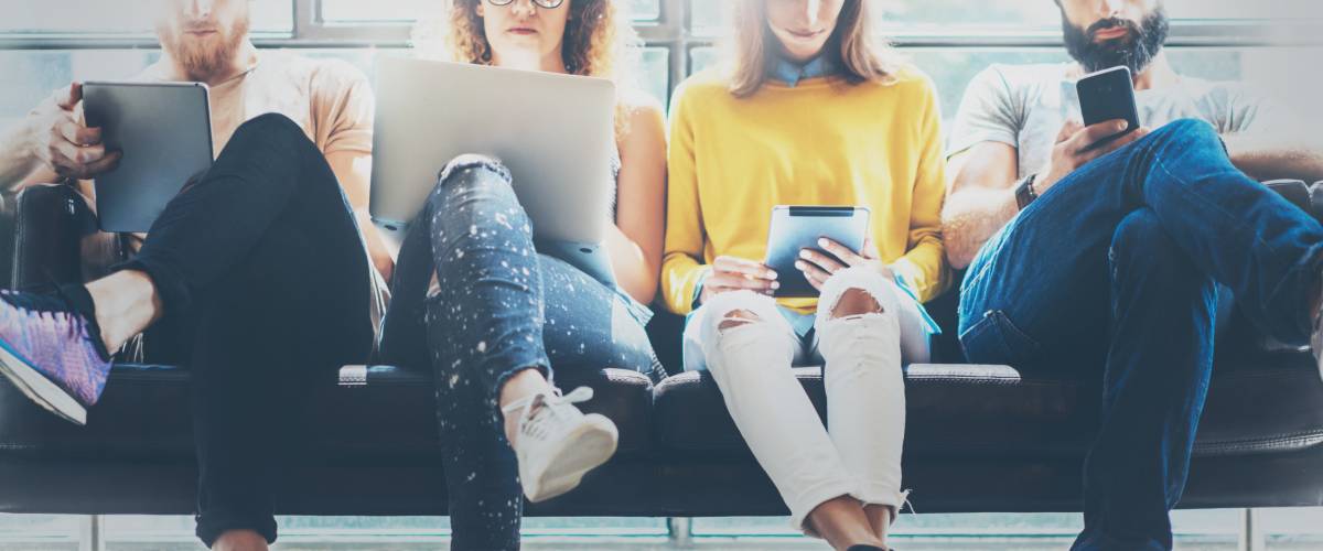 Four young people on phones and computers