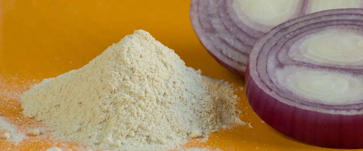 Pile of red Onion powder and red onion slides on orange background. Selective focus.