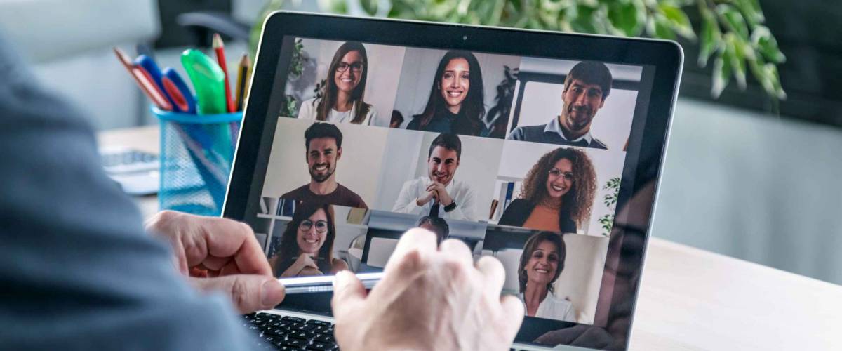 Back view of male employee speaking on video call with diverse colleagues on online briefing with laptop at home.