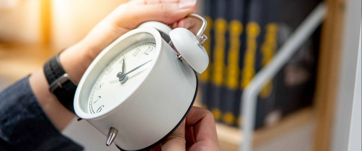 Male hand adjusting or changing the time on white clock. Time management concept.