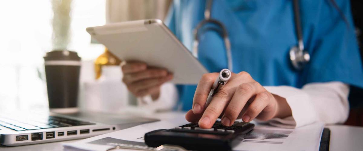 Doctor physician with stethoscope calculate medical fee costs & revenue. practitioner use calculator at Clinic.