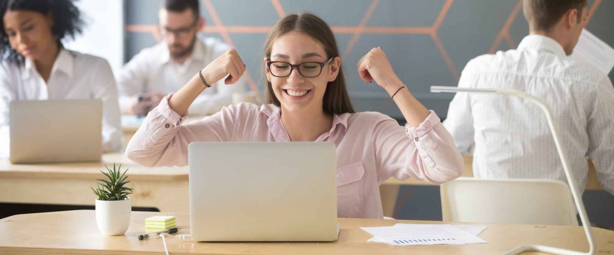 Employee feeling excited celebrating great email news looking at laptop in coworking office room