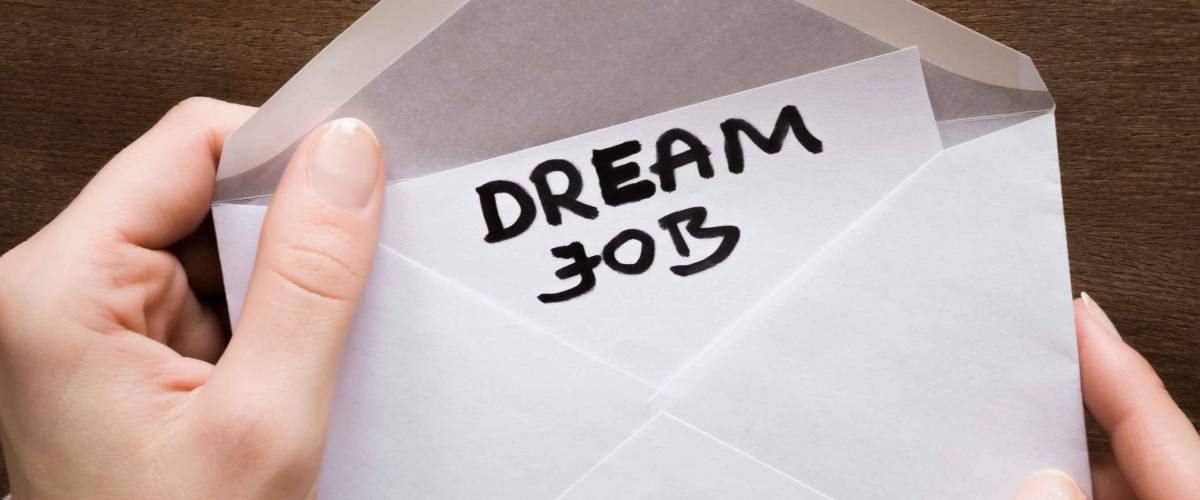Woman's hands holding an opened envelope with inscription dream job.