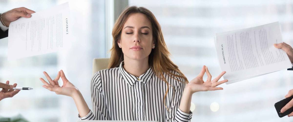 Calm female executive meditating taking break at work for mental balance,
