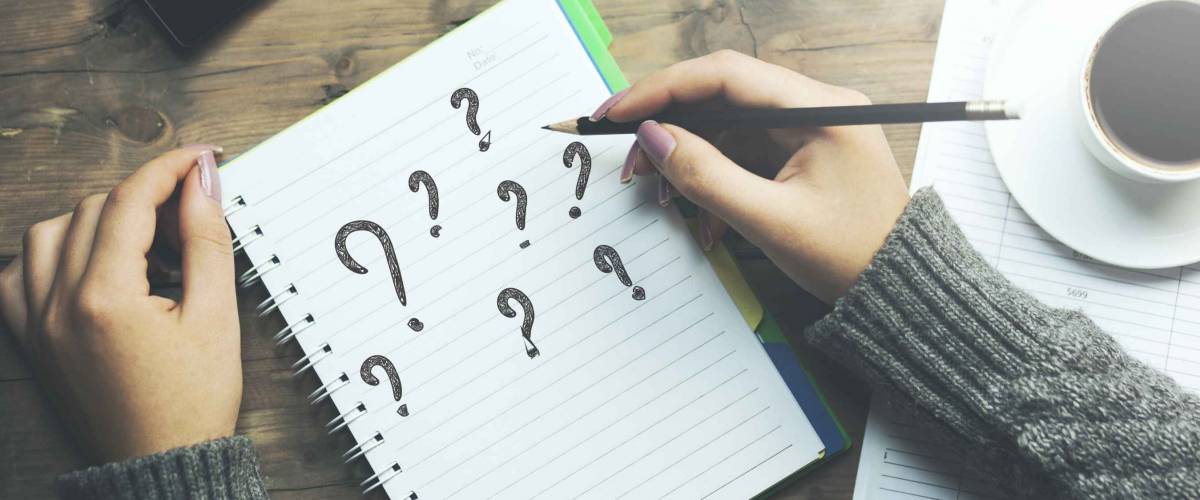 question mark on notebook with woman hand pencil and phone