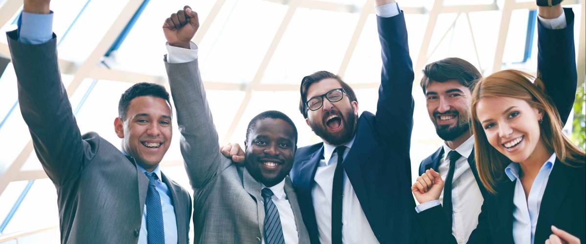 Group of ecstatic business partners looking at camera with raised arms