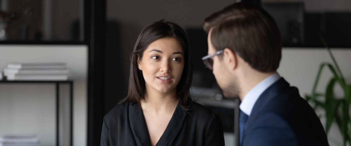 Concentrated millennial female candidate answering question of male hr on job interview,