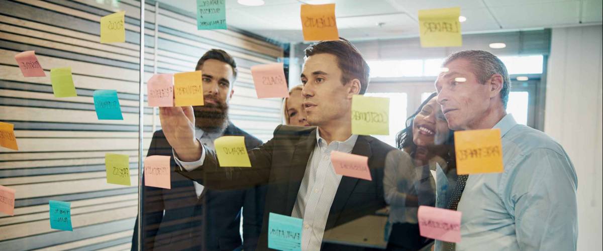 Group of business people brainstorming with sticky notes on glass window