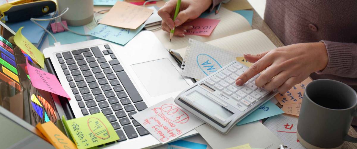 Overwhelmed woman working at messy office desk, closeup