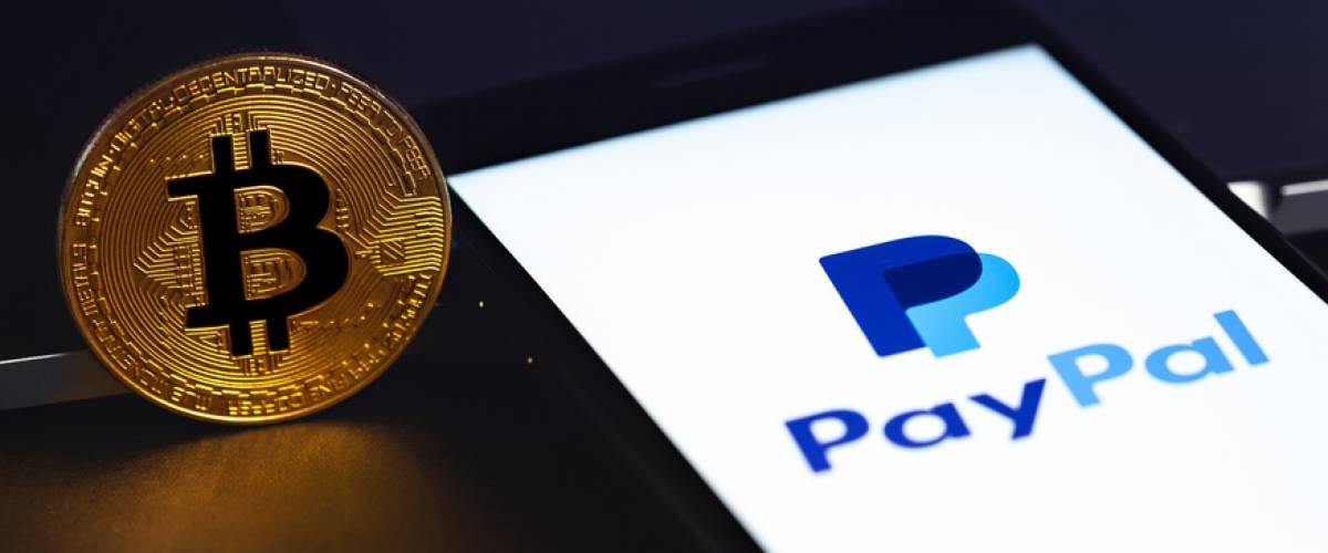 PayPal logo on the screen smartphone with bitcoin cryptocurrency in the dark.