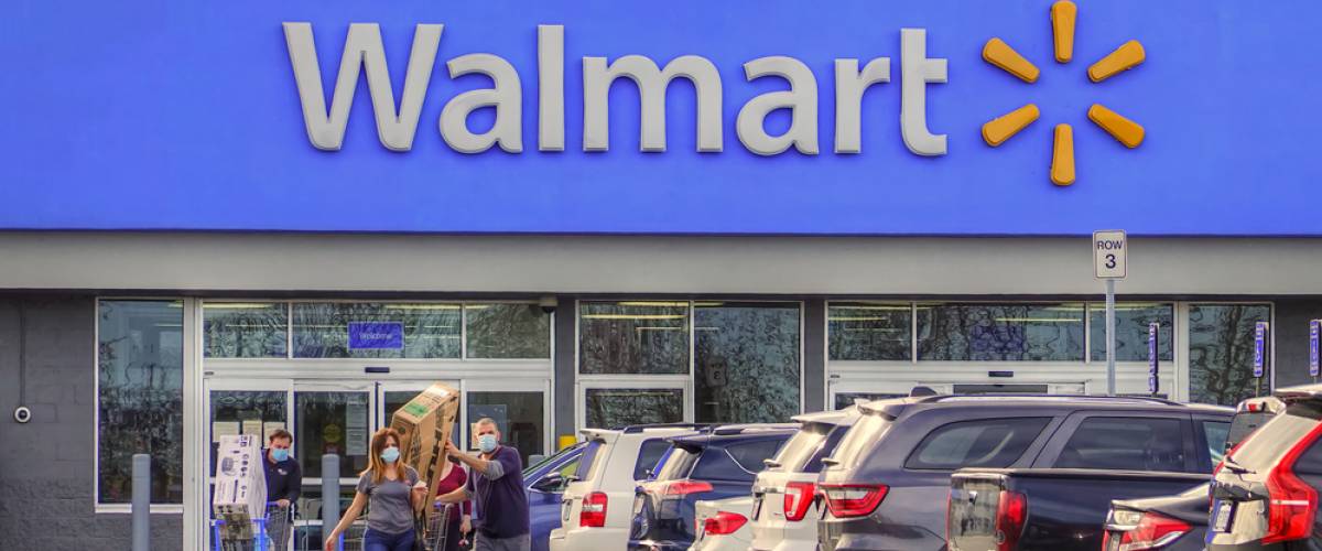 Customers wearing masks leave a Walmart in Peabody Massachusetts, with a large box sticking out of their cart.