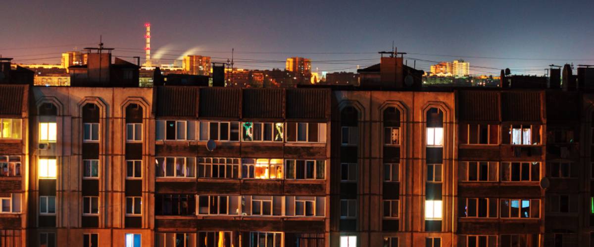 A nighttime view of an apartment buildings' windows, many of them lit up