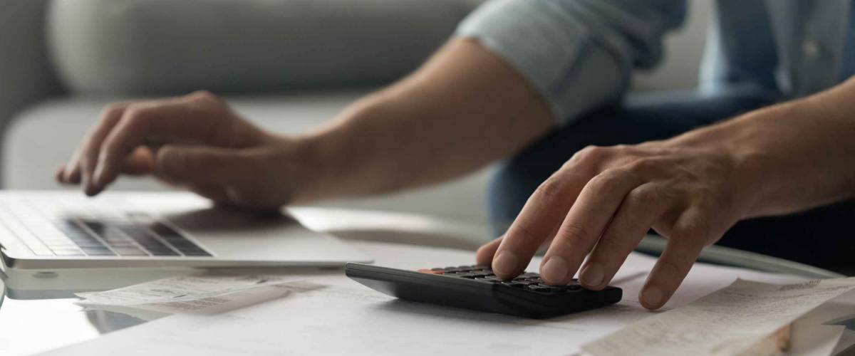 Close up of young male accountant hands make audit of expenses calculate charges based on paper documents.