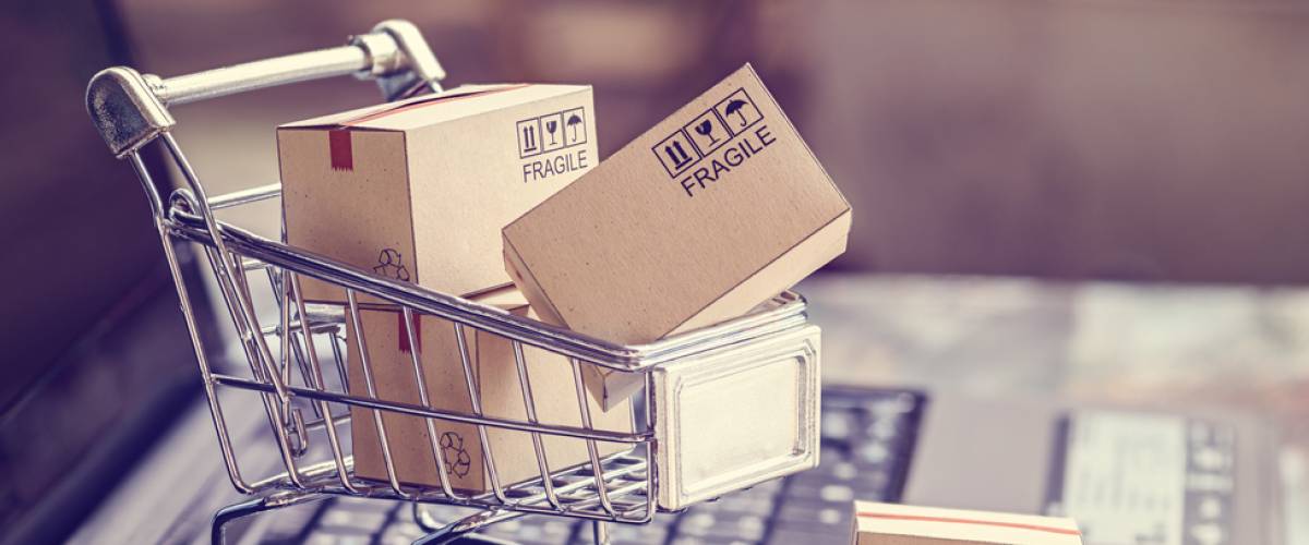 Boxes in a trolley on a laptop keyboard. Ideas about online shopping