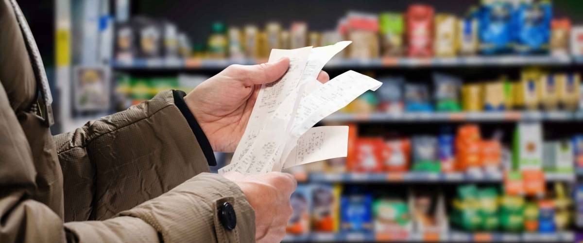 Minded man viewing receipts in supermarket and tracking prices