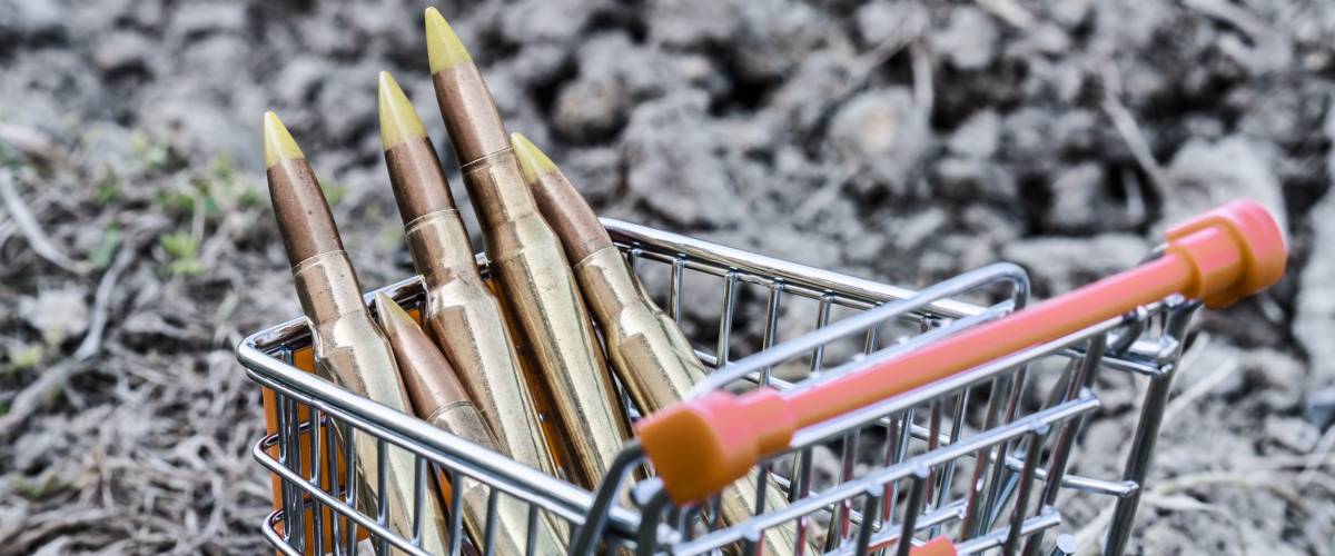 close up of orange chrome shopping cart with bullets on dirty clay