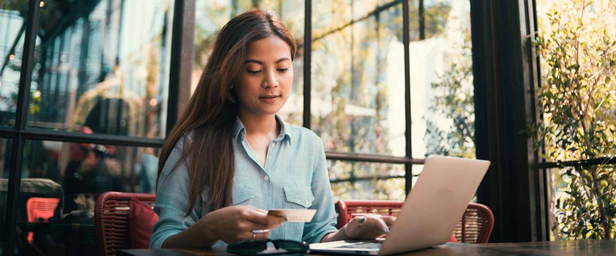 Asian woman using credit card shopping online in coffee shop vintage color tone