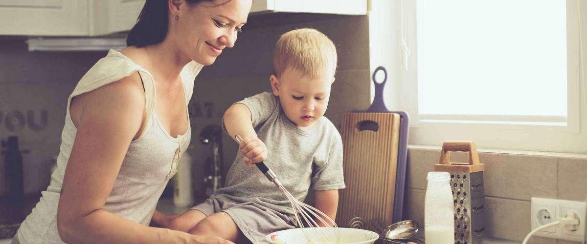 Mom with her 2 year old child cooking in the kitchen, casual lifestyle