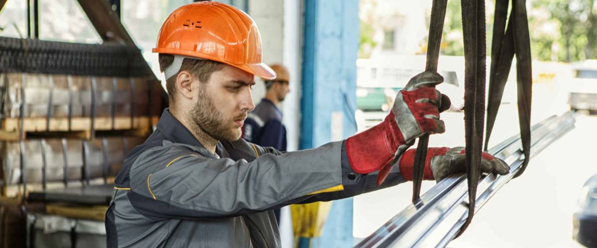 Young bearded worker in a hardhat and protective uniform working at the metal factory copyspace profession occupation engineer builder manufacturing operating concept
