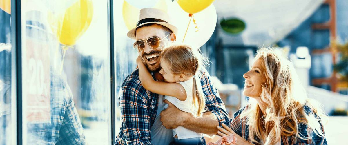 Happy family with shopping bags and ballons walking on street.